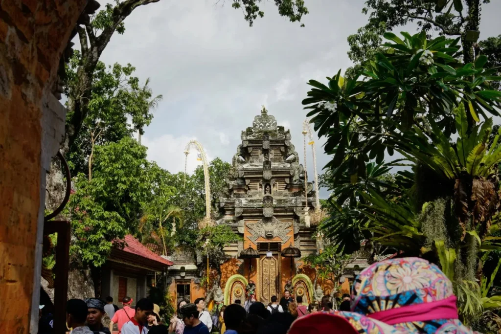 Visitors walk toward the main entrance of Ubud Palace surrounded by tropical trees and Balinese architecture.