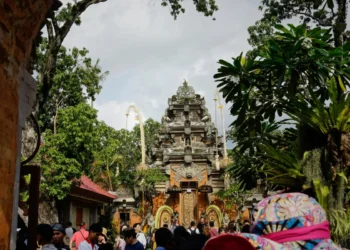 Visitors walk toward the main entrance of Ubud Palace surrounded by tropical trees and Balinese architecture.