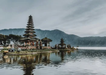 Ulun Danu Beratan Temple stands on Lake Beratan, surrounded by mountains and calm water.