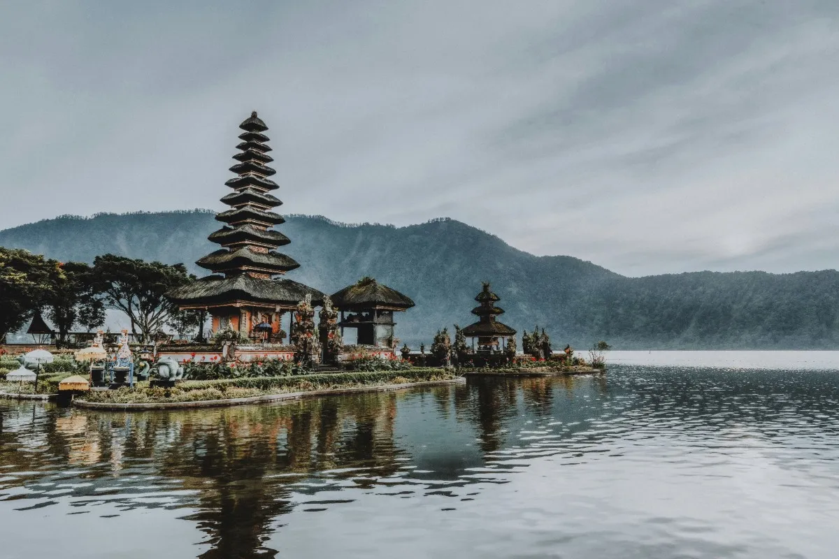 Ulun Danu Beratan Temple stands on Lake Beratan, surrounded by mountains and calm water.