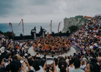 Performers perform the Kecak dance at Uluwatu Temple, surrounded by a large audience overlooking the ocean.