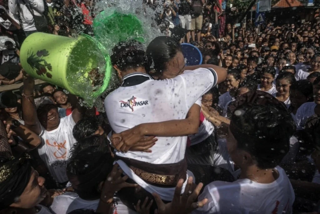 Participants celebrate Omed-Omedan as a crowded water ritual, with people pouring water over young participants in Denpasar.